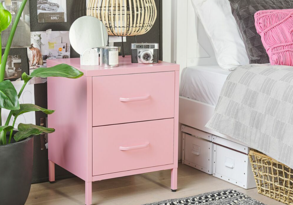 Primăvara în dormitor. Noptieră roz, patr matimonial alb, lenjerie pat, chiveci cu flori, perne roz, cutie depozitare, coș rufe.