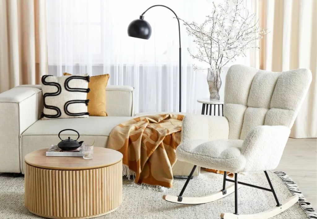Hygge de primăvară. Fotoliu balansoar relax, lampă de podea, divan bej, măsuță cafea din lemn. Pătură.